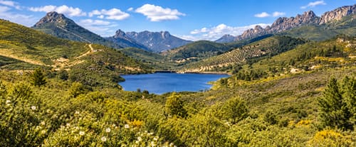 Lago de montaña rodeado de colinas verdes y picos cerca de El descanso del peregrino en Guadalupe, Cáceres