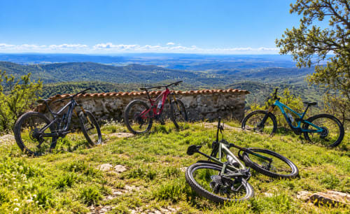 Bicicletas de montaña descansan en el pasto con vistas al valle cerca de El descanso del peregrino en Guadalupe, Cáceres