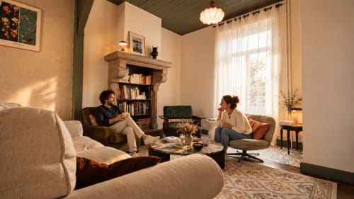 Coin salon cosy de la Maison 1903 B&B à Trévou-Tréguignec avec deux hôtes conversant près de la cheminée