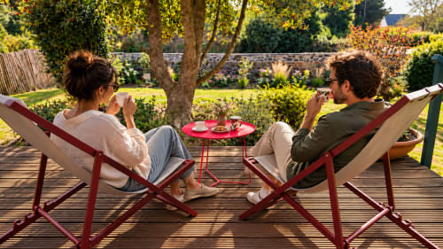 Couple relaxant dans des transats sur la terrasse en bois de La Maison 1903 B&B, Trévou-Tréguignec, vue sur le jardin