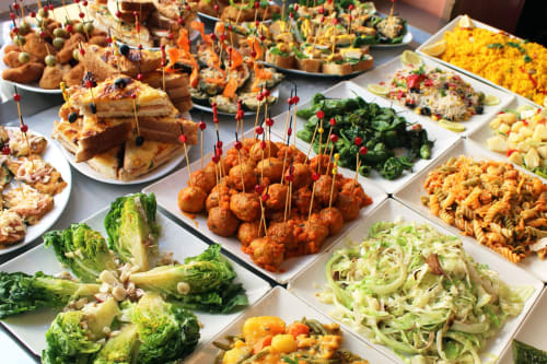 Buffet del Hostal San Vicente II Sevilla con aperitivos fritos, verduras frescas, ensaladas de pasta y acompañamientos coloridos