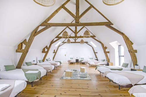 Chambre spacieuse du dortoir au Domaine Du Grand Fort avec poutres en bois, lits blancs et accents verts