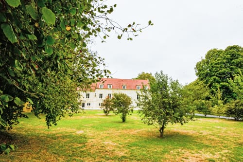 Manoir du Domaine du Grand Fort aux toits en terre cuite, entouré de jardins verdoyants et d'arbres en Normandie, France