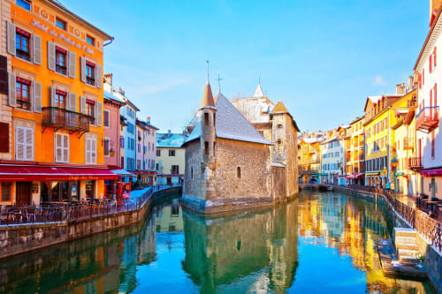 Bâtiments colorés au bord du canal et église historique à Annecy, destination hôtelière près de Morzine