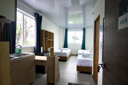 Habitación espaciosa en Vamos pa San Andrés Isla BnB con camas gemelas, cocineta, muebles de madera y ventanas con vista al mar