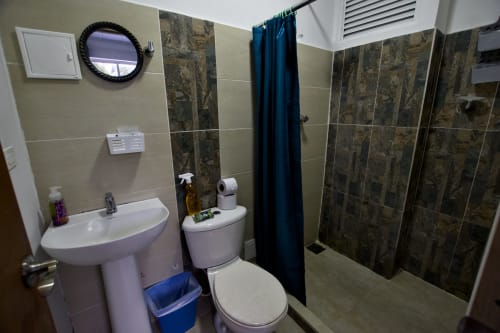 Baño moderno con lavamanos pedestal, inodoro y ducha tipo walk-in en Vamos pa San Andrés Isla BnB en San Andrés, Colombia