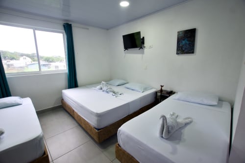 Luminosa habitación en Vamos pa San Andrés Isla con múltiples camas, TV, vista al mar y comodidades modernas