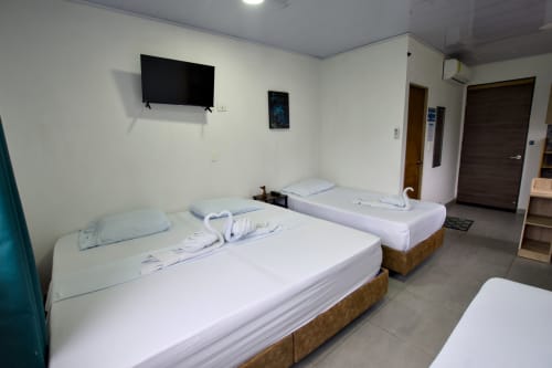 Camas gemelas con sábanas blancas en apartamento moderno de Vamos pa San Andrés Isla, con TV y vista al mar