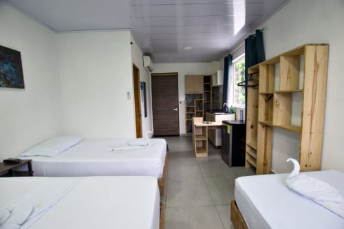 Habitación espaciosa en Vamos pa San Andrés Isla con múltiples camas, estanterías de madera, escritorio y comodidades modernas