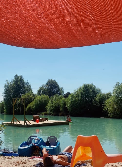 Vacancier relaxant sur la plage de sable des gîtes de Cormenin à Saint-Hilaire-sur-Puiseaux, avec rivière turquoise et bateaux gonflables