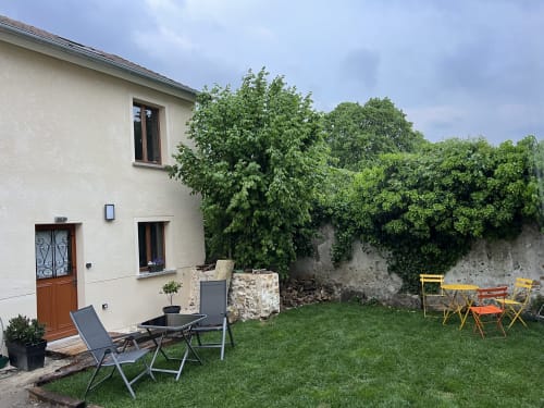 Charmant jardin de cottage aux Gîtes Les Glycines du Vexin avec coin détente, murs couverts de lierre et espaces verdoyants à Évecquemont,