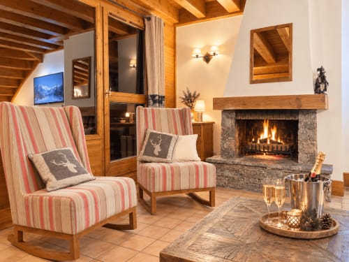 Élégant salon alpin aux Les étoiles de la plagne avec fauteuils rayés, cheminée et vues sur les montagnes à La Plagne