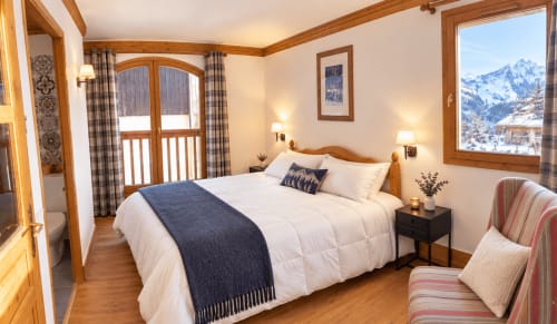 Chambre lumineuse aux Étoiles de la Plagne avec vue sur les sommets enneigés, poutres apparentes et décor alpin à La Plagne