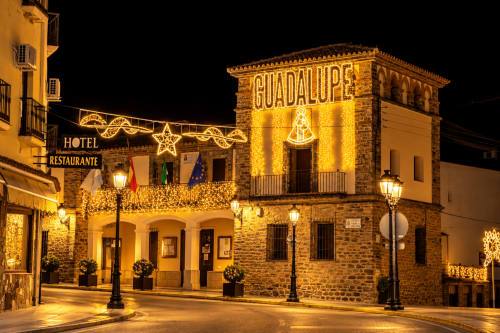 Plaza de Guadalupe de noche, edificio histórico iluminado con señal de Hotel Restaurante, Cáceres, España