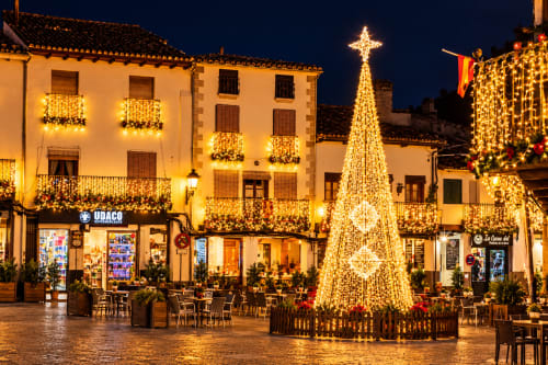 Plaza histórica en Guadalupe, Cáceres iluminada con luces navideñas doradas y árbol iluminado en El descanso del peregrino