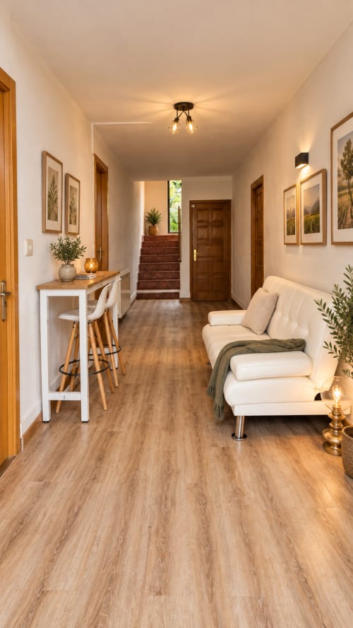Pasillo moderno en apartamento de Mutriku con suelos de madera, asientos color crema y escaleras hacia el dormitorio
