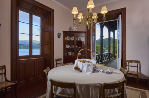 Elegante sala de jantar na casa de hóspedes Casa da Lagoa com vista para o lago, mesa redonda, lustre e acesso à varanda em Furnas, São