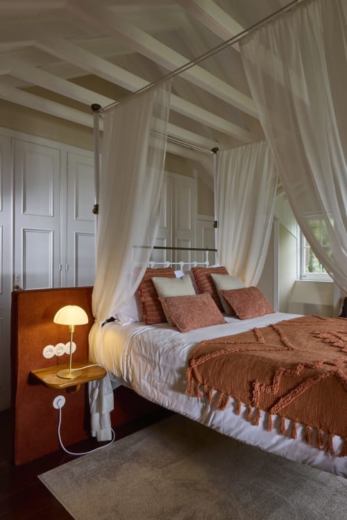 Cama com dossel elegante, roupa de cama em tons de ferrugem e cortinas translúcidas creme na Casa da Lagoa, Furnas, São Miguel