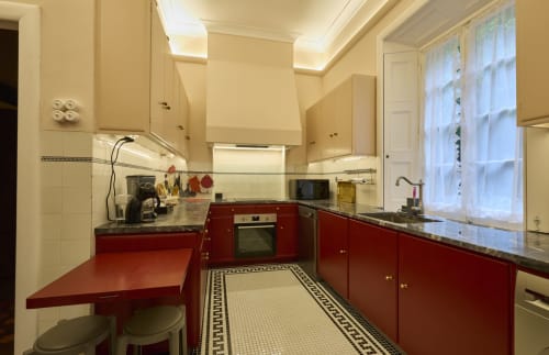 Cozinha vermelha e creme com bancadas em granito, piso em azulejo tradicional e vista para a janela na casa de campo Casa da Lagoa