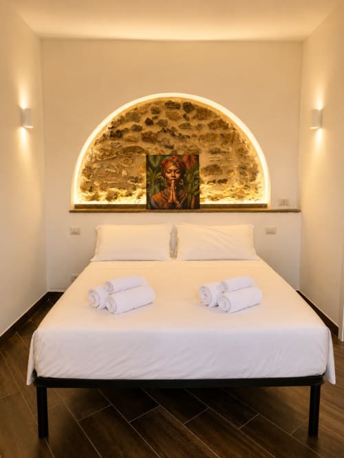 Camera moderna all'hotel Habemus di Rocca di Papa con nicchia in pietra ad arco, biancheria bianca, asciugamani arrotolati e illuminazione calda