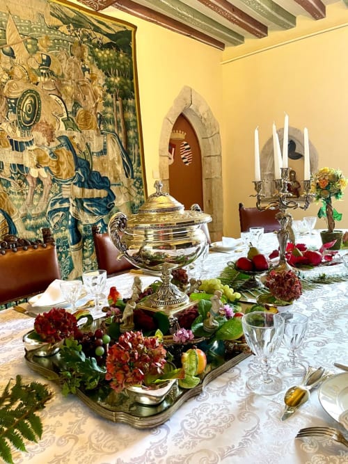 Élégante salle à manger du Château de Servigny avec table dressée, soupière dorée, candélabre et tapisserie historique