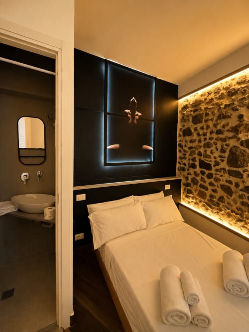 Camera moderna dell'Habemus Cuore di Rocca con letto, parete in pietra, nicchia illuminata e bagno privato