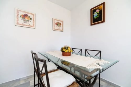 Elegante comedor en Barrosa Home con sillas negras, obras de arte floral y flores amarillas en la mesa