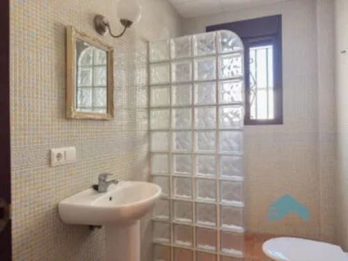 Baño moderno en Barrosa Home con lavamanos pedestal, mampara de ducha de bloques de vidrio y paredes alicatadas