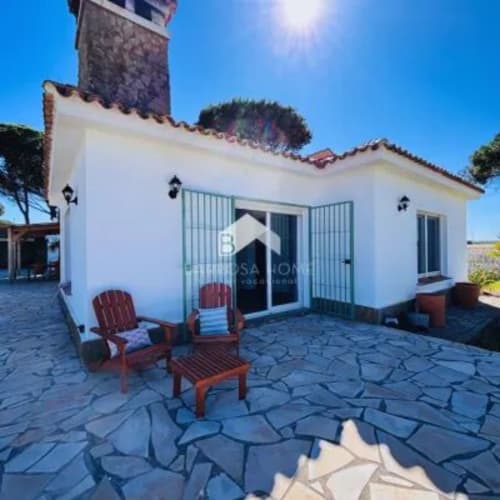 Villa Barrosa encalada con azulejos azules en patio, sillas Adirondack rojas y torre de piedra bajo cielo despejado español