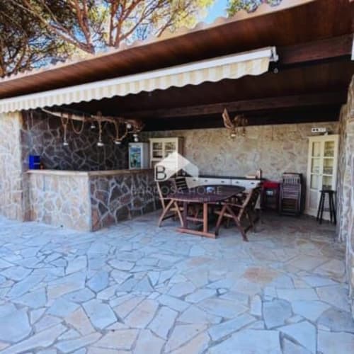 Patio de Barrosa Home con suelo de piedra, mesa de comedor, barra y toldo retráctil en España