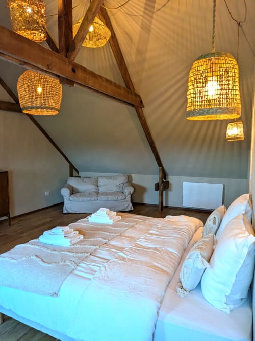 Chambre Baobab du Domaine De La Souche avec luminaires en osier tressé, plafond à poutres et vue sur le jardin à Rexpoëde