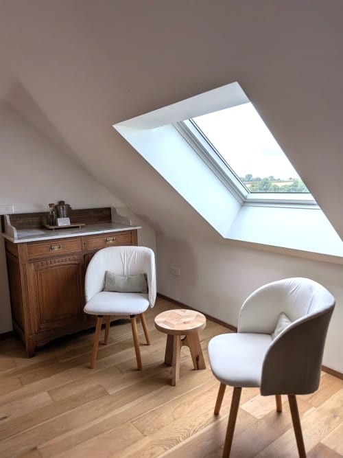 Chambre douillette sous les combles avec lucarne, mobilier bois, chaises blanches et vue sur le jardin au Domaine De La Souche