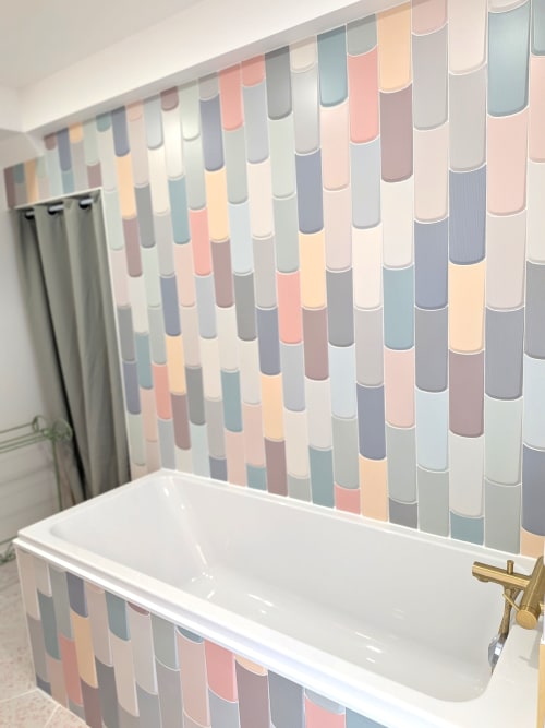 Baignoire blanche moderne avec mur de carreaux rayés colorés dans la salle de bain du Domaine De La Souche