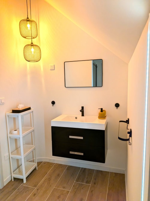 Salle de bain moderne de la Domaine De La Souche avec vasque noire, miroir blanc, suspensions dorées et parquet