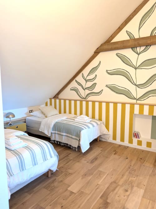 Chambre lumineuse sous les toits au Domaine De La Souche avec lits jumeaux, mur à rayures jaunes, papier peint botanique et poutres en bois
