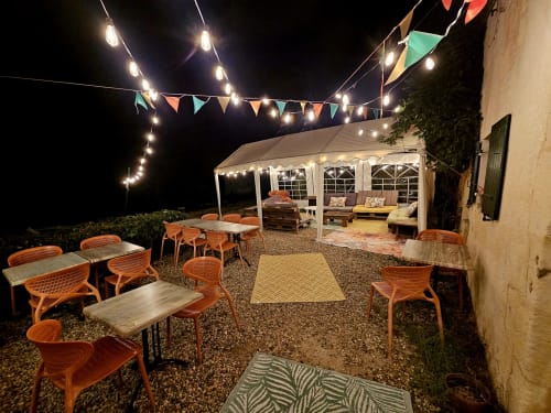 Cour du Logis de Chenac la nuit avec salon de bistrot, guirlandes lumineuses et chapiteau à Chenac-Saint-Seurin-d'Uzet