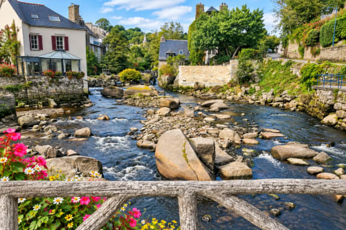 La rivière Aven traversant Pont-Aven, dans le Finistère Sud, entre rochers, maisons bretonnes en pierre et fleurs colorées.