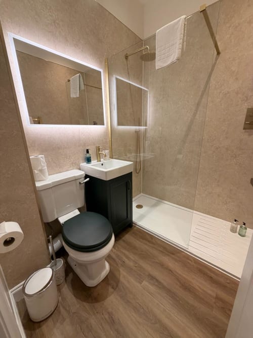 Modern bathroom at Royal Chambers Glasgow with toilet, sink, shower, and lit mirror in apartment Chambers No 3