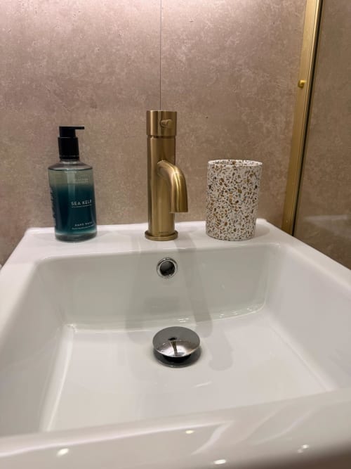 White bathroom sink with brass faucet, sea kelp hand wash, and speckled cup at Royal Chambers Glasgow