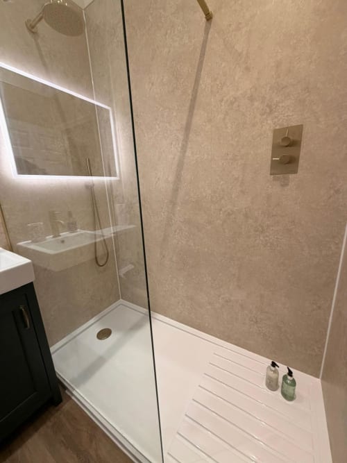 Modern bathroom at Royal Chambers Glasgow with rainfall showerhead, glass enclosure, and white tile flooring.
