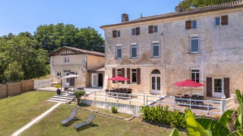 Terrasse du Domaine de Pimpine avec parasols rouges, bâtisses en pierre et jardins aménagés à Galgon, France