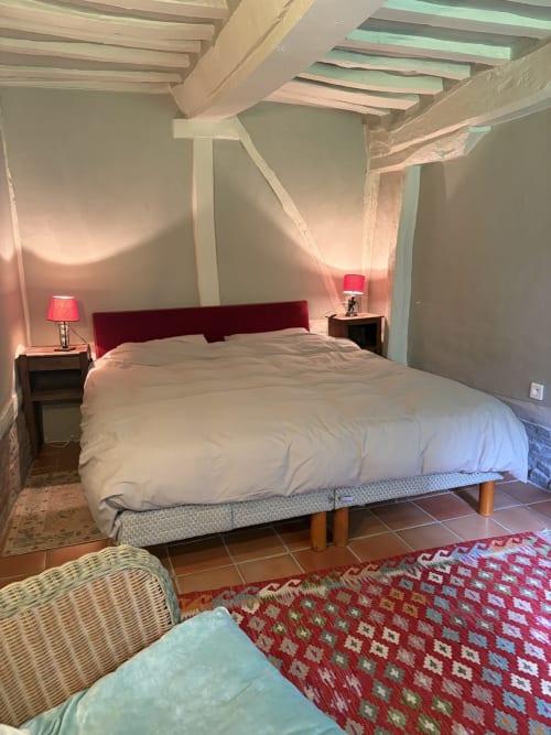 Chambre mansardée douillette avec tête de lit en velours rouge, poutres apparentes et ambiance chaleureuse à la villa Mon Week End A La Mer