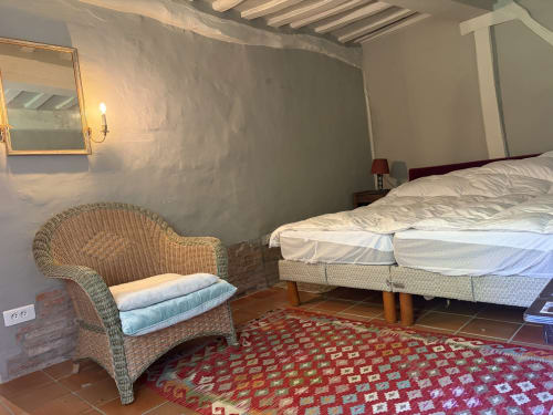 Chambre douillette de la villa Mon Week End A La Mer avec fauteuil en osier, lit et tapis rouge motifs à Varengeville-sur-Mer