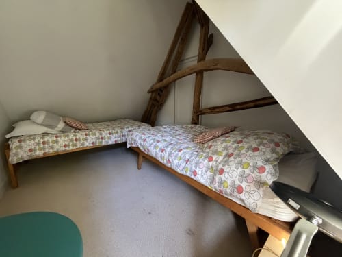 Chambre mansardée douillette avec deux lits simples, linge de lit fleuri coloré, poutres apparentes, à la villa Mon Week End A La Mer