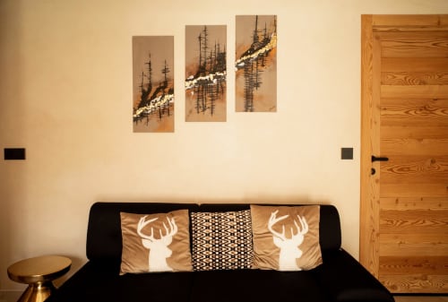 Modern chalet living room at Névalia with black sofa, deer pillows, and alpine forest wall art
