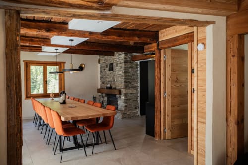 Modern rustic dining area at Chalet Névalia in Ceillac with wooden beams, stone fireplace, and mountain views