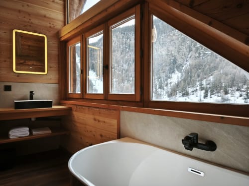 Luxury bathroom at Chalet Névalia with freestanding tub overlooking snowy Ceillac mountains