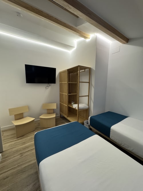 Chambre twin de l'Hôtel Oreneta avec deux lits, étagères en bois, téléviseur et éclairage moderne à Gironella