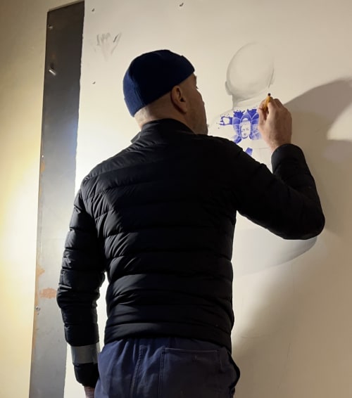 Man installing white wall decor at Domaine de l'Ocrerie B&B in Pourrain, France