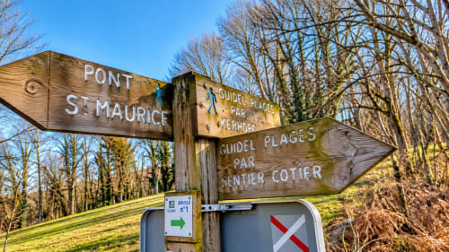 Panneaux de randonnée en bois indiquant Pont Saint-Maurice et Guidel-Plages par le sentier côtier, dans le Morbihan en Bretagne Sud.